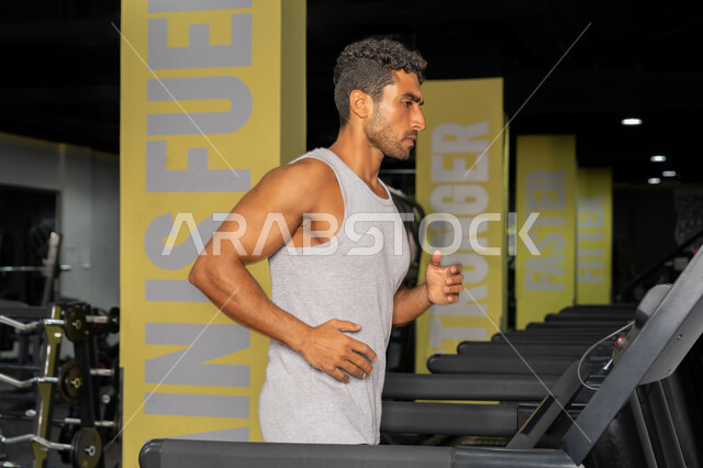 حرق الدهون وتقليل الوزن، رجل عربي خليجي إماراتي يرتدي الملابس الرياضية يقوم بالتدريب على جهاز المشي الكهربائي، شاب سعودي يركض على التريدميل، مفهوم الرشاقة واللياقة البدنية، المحافظة على أسلوب حياة صحي، أنشطة ورياضات لتقوية العضلات