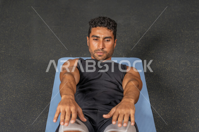 حرق الدهون وتقليل الوزن، رجل سعودي يمارس أنشطة لتقوية العضلات، شاب عربي خليجي إماراتي يرتدي الملابس الرياضية يقوم بممارسة تمارين الإحماء، إيماءات القوة والثقة، مفهوم المحافظة على أسلوب حياة صحي، نشاط بدني للحفاظ على الصحة واللياقة الجسدية