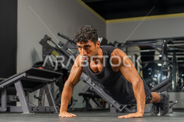 تقوية الأعصاب والعضلات، المحافظة على توازن الجسم بواسطة حركة البلانك، رجل عربي خليجي إماراتي يرتدي الملابس الرياضية يقوم بممارسة تمارين الضغط, أسلوب حياة صحي، مفهوم الرشاقة واللياقة البدنية, شاب سعودي يتمرن داخل النادي الرياضي