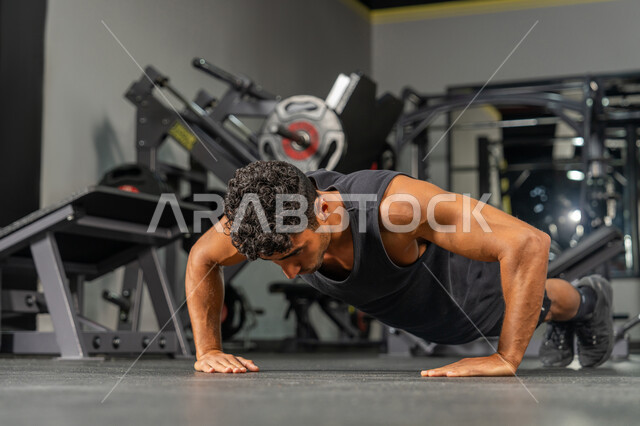 المحافظة على توازن الجسم بواسطة حركة البلانك، رجل عربي خليجي إماراتي يرتدي الملابس الرياضية يقوم بممارسة تمارين الضغط, تقوية الأعصاب والعضلات، أسلوب حياة صحي، مفهوم الرشاقة واللياقة البدنية, شاب سعودي يتمرن داخل النادي الرياضي