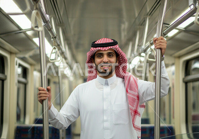 الإمساك بالعامود الحديدي للحفاظ على السلامة, تيسير الحركة المرورية للشعب السعودي, صورة مقربة لرجل عربي خليجي سعودي مبتسم يرتدي الثوب التقليدي والشماغ  يقف في مترو الرياض, النظر إلى الكاميرا بإيماءات السعادة والرضا بالخدمات الحديثة, وسائل المواصلات في المملكة