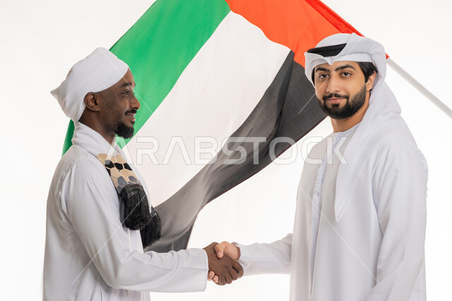 ذكرى يوم العلم 3 نوفمبر, الاحتفال باليوم الوطني الإماراتي 2 ديسمبر, مفهوم المصافحة والاتفاق, الأعياد والمناسبات الوطنية, بورتريه مقرب لشاب عربي خليجي إماراتي يرتدي الكندورة والغترة البيضاء يصافح رجل سوداني, خلفية بيضاء