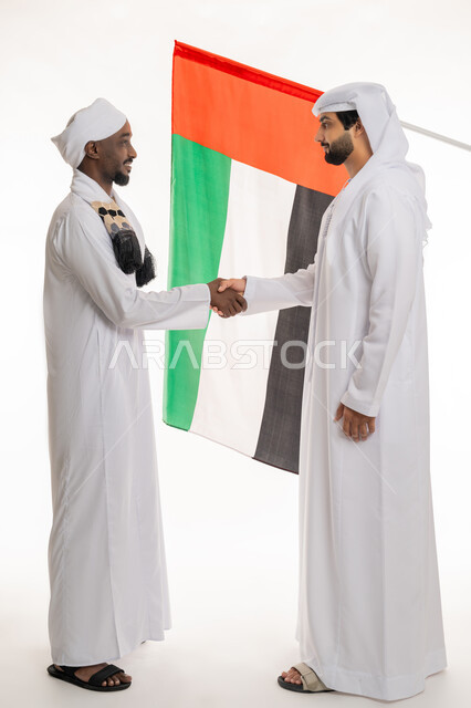 Celebrating UAE National Day December 2, National Holidays and Events, Flag Day Anniversary November 3, Handshake and Agreement Concept, Portrait of a young Emirati Gulf Arab man wearing a white kandura and ghutra shaking hands with a Sudanese man, full body, white background