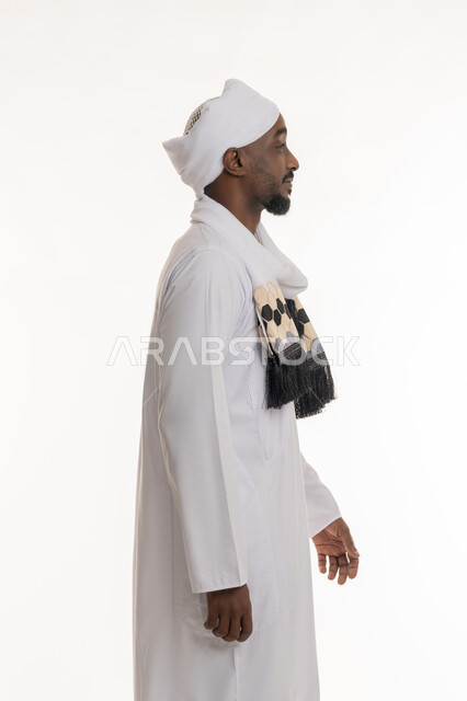 الاهتمام بالمظهر الخارجي, مفهوم الأناقة والرجولة, بورتريه من الجانب لرجل عربي سوداني مبتسم يرتدي الجلابية والعمامة السودانية يقف بتعابير الثقة والاعتزاز بالنفس, خلفية بيضاء
