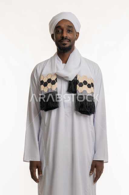 Standing up straight and upright, concept of elegance and masculinity, concern for outward appearance, portrait of a smiling Sudanese Arab man wearing a Sudanese galabiya and turban looking at the camera with gestures of happiness and pleasure, white background
