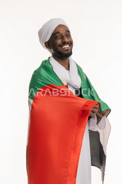 ذكرى اليوم الوطني الإماراتي 2 ديسمبر, استذكار يوم العلم 3 نوفمبر, تعابير الحب والانتماء, الاحتفال بالأعياد والمناسبات الوطنية, بورتريه لرجل عربي سوداني مبتسم يرتدي الجلابية والعمامة السودانية يضع علم الإمارات على ظهره, خلفية بيضاء