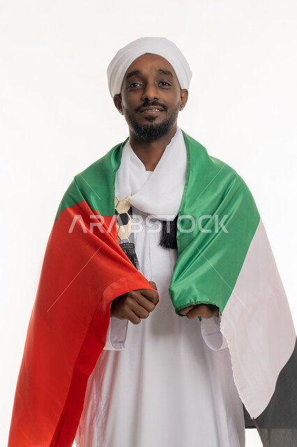 النظر إلى الكاميرا بإيماءات الحب والانتماء, الاحتفال بالأعياد والمناسبات الوطنية, اليوم الوطني الإماراتي 2 ديسمبر, استذكار يوم العلم 3 نوفمبر, بورتريه لرجل عربي سوداني يرتدي الجلابية والعمامة السودانية يضع علم الإمارات على ظهره, خلفية بيضاء