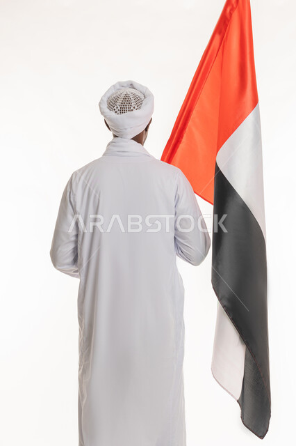 الاحتفال بالأعياد والمناسبات الوطنية, اليوم الوطني الإماراتي 2 ديسمبر, استذكار يوم العلم 3 نوفمبر, بورتريه من الخلف لرجل عربي سوداني يرتدي الجلابية والعمامة السودانية يحمل علم الإمارات العربية المتحدة, خلفية بيضاء