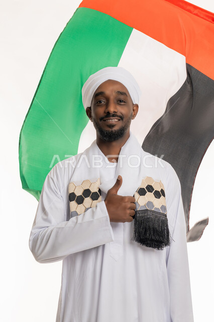 Thumbs up gesture, expressions of approval and acceptance, celebration of national holidays and occasions, UAE National Day December 2, Flag Day November 3, portrait of a Sudanese Arab man wearing a Sudanese galabiya and turban looking at the camera with gestures of happiness and pleasure, white background