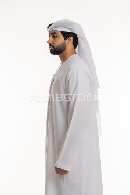 مفهوم الرجولة والأناقة, الاهتمام بالمظهر الخارجي, الوقوف باستقامة واعتدال, بورتريه من الجانب لرجل عربي خليجي إماراتي يرتدي الكندورة والغترة البيضاء ينظر إلى شيء ما, خلفية بيضاء