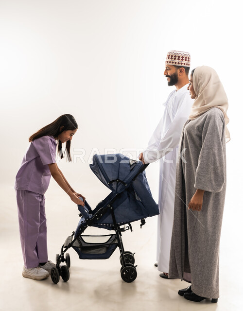 الاهتمام و الرعاية بالأولاد, أهمية الأهل ودورهم الأساسي في تربية ونشأة الأبناء, بورتريه لرجل عربي خليجي عماني يرتدي الدشداشة والكمة يقف مع زوجته وابنته ويقوم بجرعربة الأطفال، القيام بالنزهات والجولات العائلية، عائلة عمانية تقضي اوقات ممتعة، خلفية بيضاء