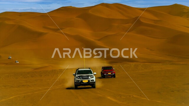 Driving a four-wheel drive vehicle (dune bashing) in the middle of the desert, fun desert activities, enjoying your favorite hobbies, an exciting adventure on the soft golden sands of the Kuwaiti deserts, safari adventures on the sand dunes