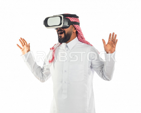 بورتريه لرجل عربي سعودي خليجي يرتدي نظارة الواقع الافتراضي, استخدام التقنيه الحديثه, الاستمتاع واللعب والتخيل في نظارة الواقع الافتراضي, تقنيه متطوره, عالم ثلاثي الأبعاد, ايماءات وجه ويدين تدل على الدهشه والتعجب والسرور, التطلع للمستقبل, رؤية 2030
