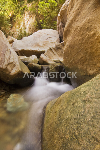 Wadi Lajab in Jazan, Saudi Arabia, blue waters between a mountain crack, rocky peaks and heights, natural rock formations, green trees and plants, famous tourist attractions