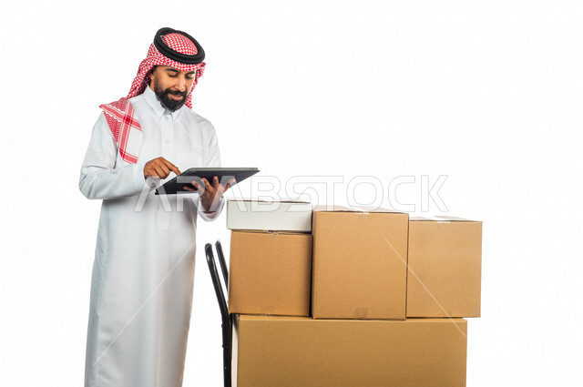 Portrait of a Saudi Arabian Gulf man working in the delivery of orders and goods to customers, online shopping, online orders, reliable shipping and delivery process, warehouse keeper, sales representative, documenting orders, confirming reservations, mak