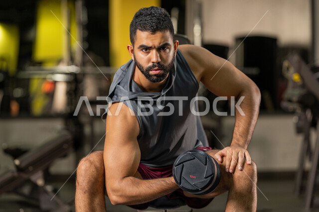 Bodybuilding, using weights, a young Arab Gulf Emirati man wearing ...