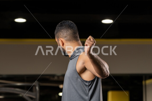 زيادة المرونة وتمديد العضلات، المحافظة على اللياقة البدنية، أهمية الرياضة لبناء جسد قوي، صورة مقربة من الجانب لرجل سعودي يمارس تمرين لتحسين وضعية الجسم والتوازن، شاب عربي خليجي اماراتي يرتدي الملابس الرياضية يتمرن حبل المقاومة المطاطي، أسلوب حياة صحي