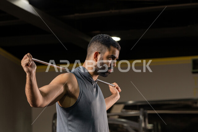 زيادة المرونة وتمديد العضلات، المحافظة على اللياقة البدنية، أهمية الرياضة لبناء جسد قوي، صورة مقربة من الجانب لرجل سعودي يمارس تمرين لتحسين وضعية الجسم والتوازن، شاب عربي خليجي اماراتي يرتدي الملابس الرياضية يتمرن حبل المقاومة المطاطي، أسلوب حياة صحي