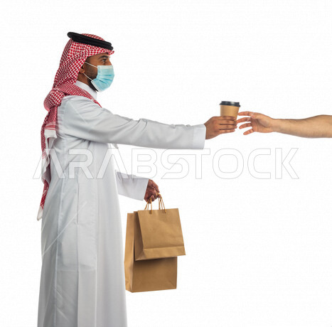 بورتريه لرجل عربي سعودي خليجي يرتدي الزي السعودي يعمل في توصيل الطلبات والبضائع للزبائن, التسوق الالكتروني, طلبات اونلاين, التسوق الذكي, عملية شراء وتوصيل موثوقه, مندوب توصيل,  خدمات التوصيل السريع, ضمان تسليم المشروبات ساخنه,الالتزام بالإحترازات الوقائيه