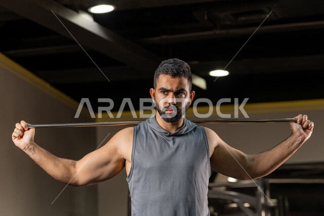 ايماءات القوة والعزم، أسلوب حياة صحي، المحافظة على اللياقة البدنية، أهمية الرياضة لبناء جسد قوي، زيادة المرونة وتمديد العضلات، صورة مقربة لرجل سعودي يمارس تمرين لتحسين وضعية الجسم والتوازن، شاب عربي خليجي اماراتي يرتدي الملابس الرياضية يتمرن حبل المقاومة المطاطي