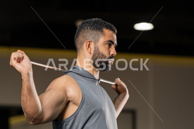 زيادة المرونة وتمديد العضلات، المحافظة على اللياقة البدنية، أهمية الرياضة لبناء جسد قوي، صورة مقربة من الجانب لرجل سعودي يمارس تمرين لتحسين وضعية الجسم والتوازن، شاب عربي خليجي اماراتي يرتدي الملابس الرياضية يتمرن حبل المقاومة المطاطي، أسلوب حياة صحي