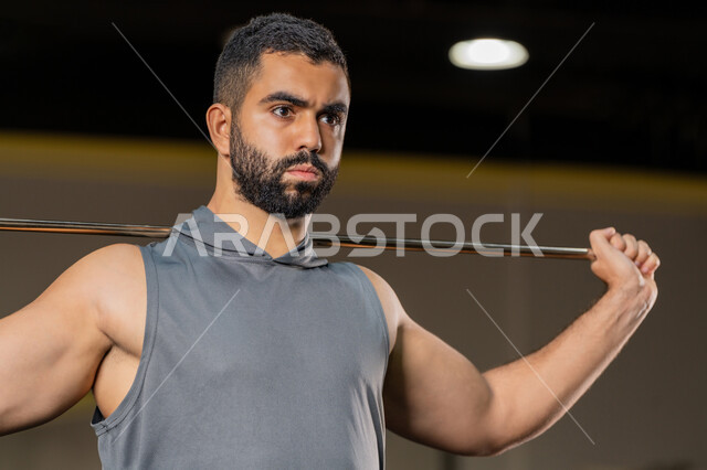 زيادة المرونة وتمديد العضلات، نشاط شبابي يساعد على اللياقة البدنية, أهمية الرياضة لبناء جسد قوي، رجل سعودي يمارس تمرين لتحسين وضعية الجسم والتوازن، شاب عربي خليجي إماراتي يرتدي الزي الرياضي يتمرن باستخدام العصا، أسلوب حياة صحي، تعابير القوة والعزم
