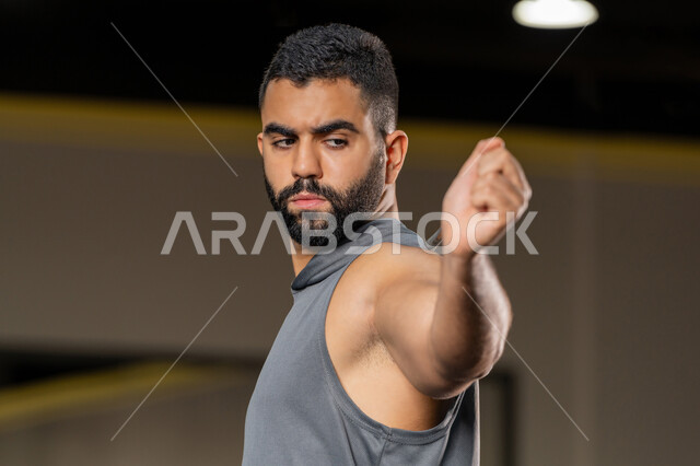 تعابير القوة والعزم، زيادة المرونة وتمديد العضلات، نشاط شبابي يساعد على اللياقة البدنية, أهمية الرياضة لبناء جسد قوي، رجل سعودي يمارس تمرين لتحسين وضعية الجسم والتوازن، شاب عربي خليجي إماراتي يرتدي الزي الرياضي يتمرن باستخدام العصا، أسلوب حياة صحي