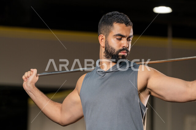 أسلوب حياة صحي، زيادة المرونة وتمديد العضلات، نشاط شبابي يساعد على اللياقة البدنية, أهمية الرياضة لبناء جسد قوي، رجل سعودي يمارس تمرين لتحسين وضعية الجسم والتوازن، شاب عربي خليجي إماراتي يرتدي الزي الرياضي يتمرن باستخدام العصا، تعابير القوة والعزم