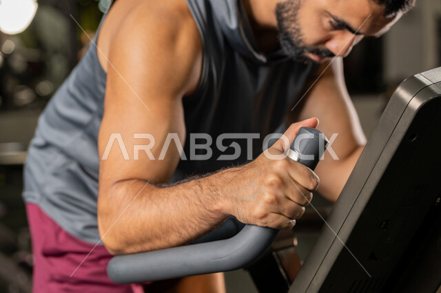 حرق السعرات الحرارية وإنقاص الوزن، نشاط شبابي يساعد على اللياقة البدنية, أهمية الرياضة لبناء جسد قوي، رجل سعودي يمارس تمرين لتحسين وضعية الجسم والتوازن، شاب عربي خليجي إماراتي يرتدي الزي الرياضي يقوم بممارسة التمارين على جهاز التجذيف، استخدام الأجهزة الرياضية