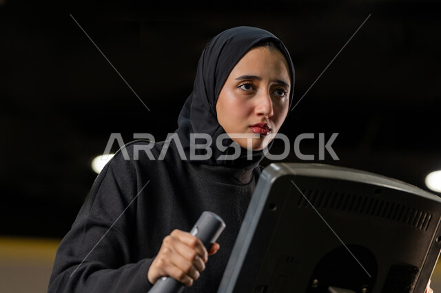إنقاص الوزن وحرق السعرات الحرارية، نشاط شبابي يساعد على اللياقة البدنية, أهمية الرياضة لبناء جسد قوي، امراة سعودية تمارس تمرين لتحسين وضعية الجسم والتوازن، شابة عربية خليجية إماراتية محجبة ترتدي الزي الرياضي تقوم بممارسة التمارين على جهاز التجذيف