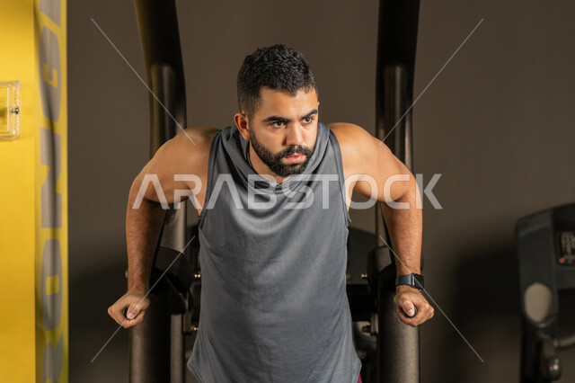 استخدام الأجهزة الرياضية، أسلوب حياة صحي، أهمية الرياضة لبناء جسد قوي، نشاط شبابي يساعد على اللياقة البدنية, رجل سعودي يمارس تمرين لتقوية عضلات الصدر، رياضة كمال الأجسام، شاب عربي خليجي إماراتي يرتدي الزي الرياضي يقوم بممارسة التمارين على جهاز الغطس المساعد