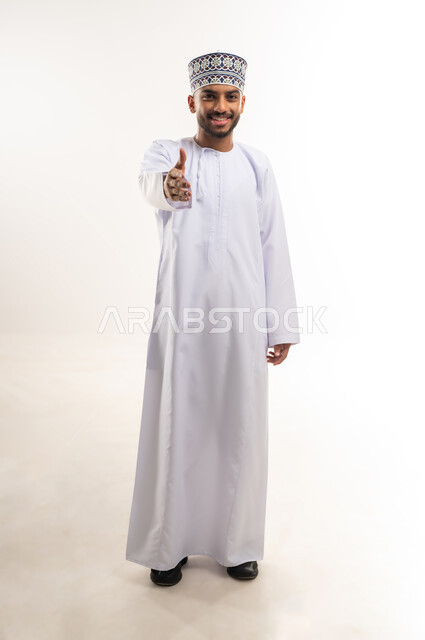 التعارف و الصداقة وتكوين العلاقات الاجتماعية, إلقاء التحية والسلام, مفهوم الاستقبال والترحيب, بورتريه لرجل عربي خليجي عماني يرتدي الدشداشة والكمة يمد كفه بتعابير المصافحة, الجسم بالطول الكامل, خلفية بيضاء
