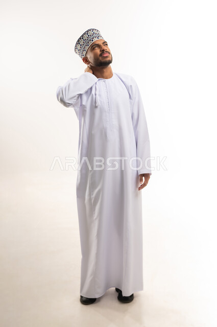وجع مفاصل و عظام الرقبة, آلام العنق والعمود الفقري, الحاجة للعلاج الفيزيائي، الإحساس بالتعب والإرهاق, بورتريه لرجل عربي خليجي عماني يرتدي الدشداشة والكمة يضع يده حول عنقه بإيماءات الألم, الجسم بالطول الكامل, خلفية بيضاء