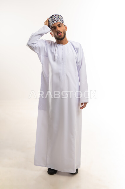 الإغفال والسهو والغفلة, التذكر المفاجئ لشيء هام، التأخر على موعد ما, بورتريه لرجل عربي عماني يرتدي الدشداشة والكمة يضع يده على رأسه بتعابير النسيان والذهول, الجسم بالطول الكامل, خلفية بيضاء
