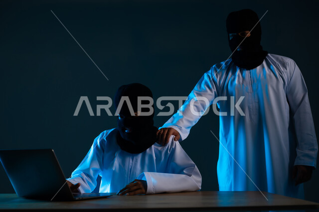 Cyber ​​security intrusion, use of computer for illegal purposes, hacking and data theft, algorithms to destroy digital accounts, close-up portrait of two masked Gulf Arab Omani hackers wearing dishdashas working in the field of hacking, blue background