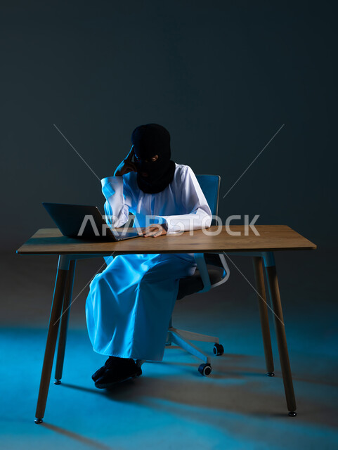 قرصنة وسرقة البيانات, تدمير الحسابات الرقمية, استخدم جهاز الحاسوب لأغراض غير مشروعة، مفهوم الجرائم الالكترونية, القدرة على تهكير الأجهزة, بورتريه لهاكر عربي خليجي عماني ملثم يرتدي الدشداشة يضع يده على رأسه بتعابير التركيز، خلفية زرقاء