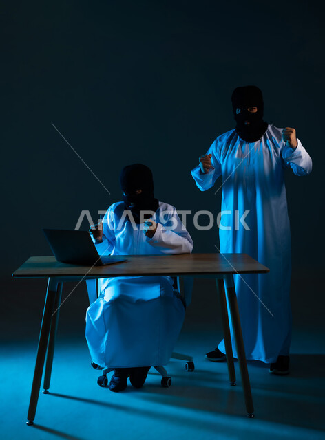 نجاح عملية تهكير وسرقة البيانات, خوارزميات لتدمير الحسابات الرقمية, استخدم جهاز الحاسوب لأغراض غير قانونية, التسلل عبر الأمن السيبراني, بورتريه لهكرين عربيين خليجيين عمانيين ملثمين يرتديان الدشداشة يرفعان قبضة يديهما بتعابير الفرح, خلفية زرقاء