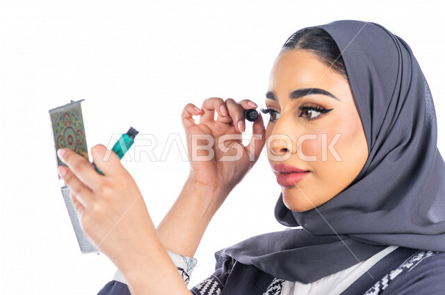 بورتريه لمرأة عربية خليجية سعودية تحمل إحدى أدوات التجميل (قلم المسكرة) لإبراز العين ، خلفية بيضاء لمرأة خبيرة بمستحضرات التجميل، التسويق لمنتجات التجميل، متجر بيع مستحضرات التجميل عبر الإنترنت ، مفهوم الإهتمام بالجمال والبشرة، ادوات مكياج تتوريال