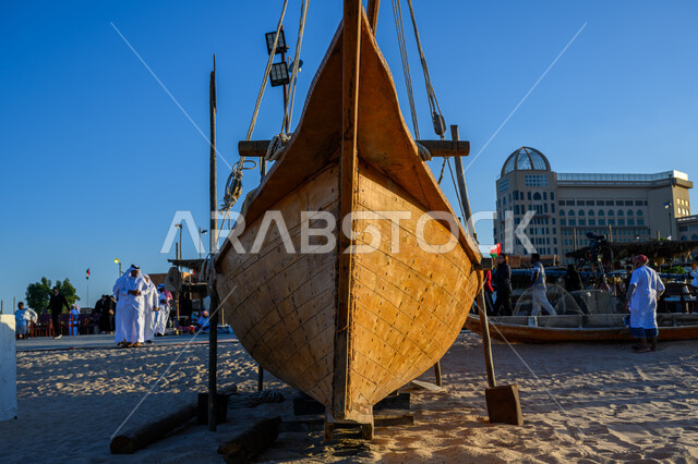 Enjoy quiet sea trips and excursions, the 14th Katara Dhow Festival, the waterfront in the State of Qatar during the day, tourist places to spend enjoyable times, a wooden boat in the middle of the sea on the Doha Corniche