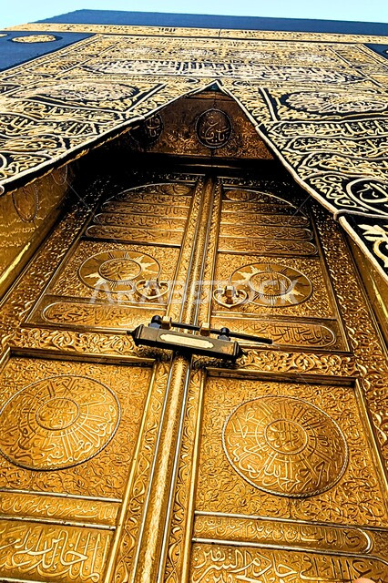كسوة الكعبة المطرزة بخيوط ذهبية وفضية، الأماكن والمعالم الإسلامية المقدسة بالمملكة العربية السعودية, صورة مقربة لباب الكعبة الذهبي المغطى بالستارة الحريرية السوداء المنقوشة بآيات من القرآن الكريم، بيت الله الحرام في الحرم المكي الشريف في مكة المكرمة