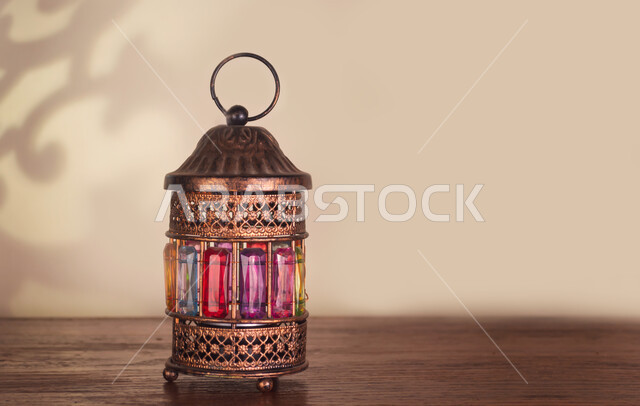 فانوس عربي معدني مزخرف على طاولة خشبية، فوانيس وتحف اسلامية تقليدية للاحتفال بقدوم شهر الخير، أنوار ومصابيح في الأجواء الرمضانية الروحانية، إضاءة وزينة شهر رمضان المبارك