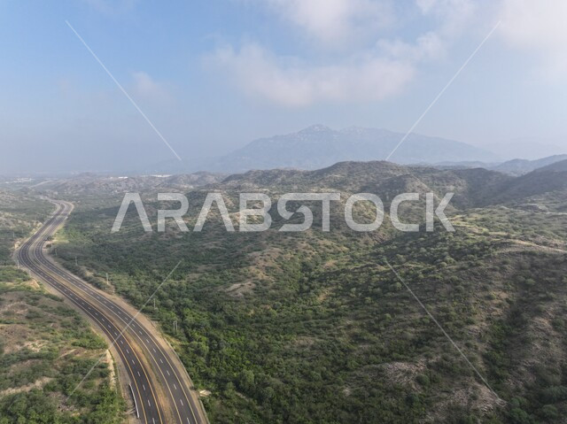 طريق اسفلتي على سفوح الجبال في محافظة الداير، الاماكن السياحية المشهورة، النباتات الخضراء والأشجار على القمم والمرتفعات الجبلية في منطقة جازان، المناظر الطبيعية المتميزة في المملكة العربية السعودية