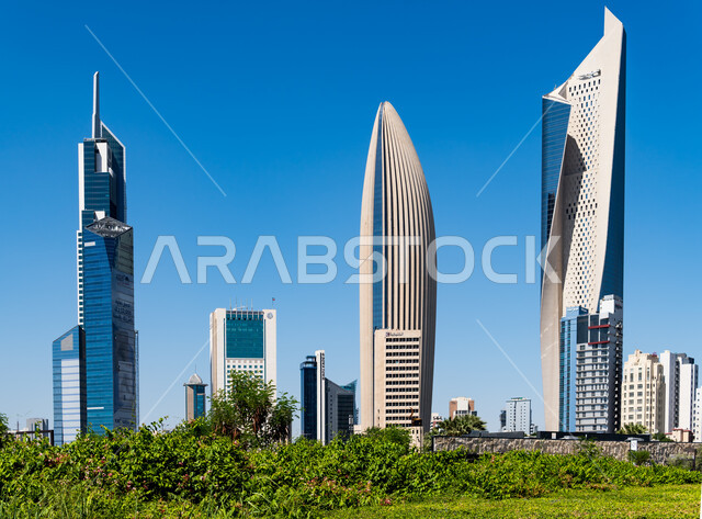 Architectural art of towers and skyscrapers, modern urban growth and development of buildings in Kuwait City, residential and commercial facilities and famous tourist attractions, Al Hamra Tower, National Tower and Raya Tower in the State of Kuwait, blue sky background