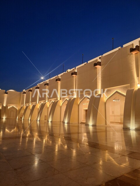 Architectural engineering art of building mosques in the State of Qatar, the outer courtyard of Imam Abdul Wahab Mosque illuminated at night in the Dafna area, sacred religious landmarks, the call of Muslims to perform duties and prayers