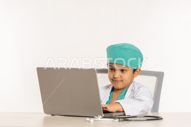 تدوين نتائج الفحوصات، الهدف والطموح المستقبلي، استخدام الاجهزة التقنية الحديثة، بورتريه مقرب لولد عربي خليجي اماراتي يرتدي المعطف الأبيض يضع السماعة الطبية يجلس خلف المكتب يعمل على الحاسوب المحمول، فتى سعودي بقوم بإعداد التقارير، صورة لكامل الجسم، خلفية بيضاء