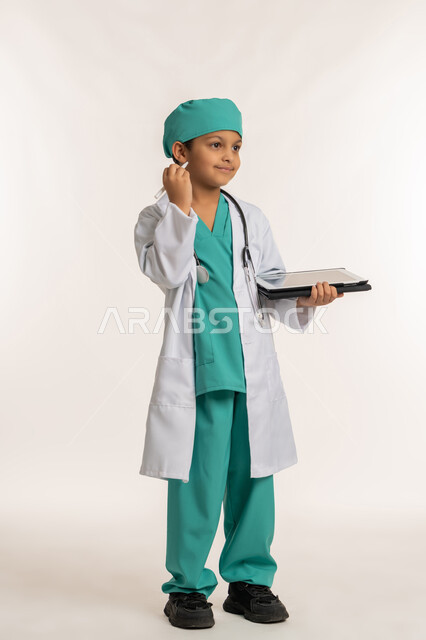 الأهداف والطموحات المستقبلية بالعمل في العيادات والمشافي، تدوين نتائج الفحوصات، تحديد مهنة المستقبل، بورتريه لصبي عربي خليجي اماراتي يرتدي المعطف الأبيض والسماعات يحمل بيده جهاز التابلت، ولد سعودي بقوم بإعداد التقارير الطبيه، صورة لكامل الجسم، خلفية بيضاء
