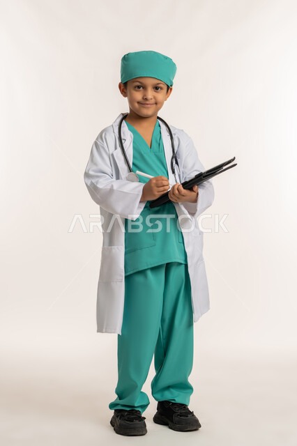 تدوين نتائج الفحوصات، الهدف والطموح المستقبلي بالعمل في العيادات والمشافي، استخدام قلم التابلت للنقر على شيء ما، بورتريه لفتى عربي خليجي اماراتي يرتدي المعطف الأبيض والسماعات يحمل جهاز لوحي، ولد سعودي بقوم بإعداد التقارير الطبيه، صورة لكامل الجسم، خلفية بيضاء