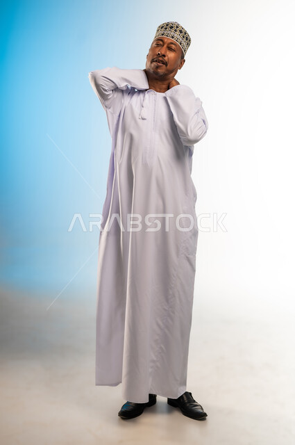 التهاب المفاصل والعضلات في الرقبة، آلام العظام والعمود الفقري، الحاجة للذهاب إلى الطبيب والمعاينة، ضرورة الاسترخاء وأخذ قسط من الراحة، بورتريه لرجل عربي خليجي عماني يرتدي الدشداشة والكمة يضع يده حول عنقه بإيماءات التألم، الجسم بالطول الكامل، خلفية ملونة