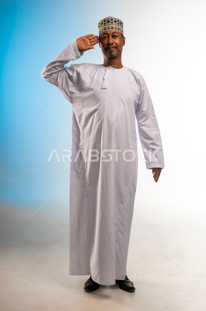 إلقاء التحيه والسلام, مفهوم الاستقبال والترحيب, التعارف و الصداقه وتكوين علاقات, بورتريه لرجل عربي خليجي عماني مبتسم يرتدي الدشداشة و الكمه ينظر الى الكاميرا يرفع كفه للمصافحة بإيماءات السرور والبشاشة، خلفية ملونة