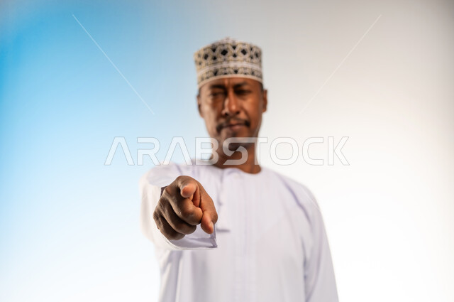 Different finger gestures and movements, tapping and pressing expressions, close-up portrait of a smiling Omani Gulf Arab man wearing a dishdasha and a sleeve looking at the camera pointing his index finger in a direction, colored background